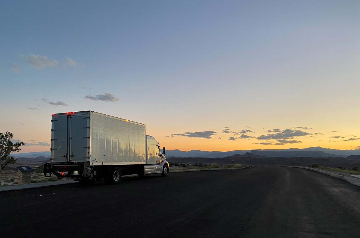 A Displays Fine Art Services truck stopped on a road in Utah facing the sunset behind the mountains.