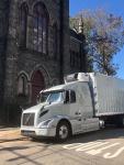 A straight truck owned by Displays Fine Art Services parked in front of a Roman Catholic church building.